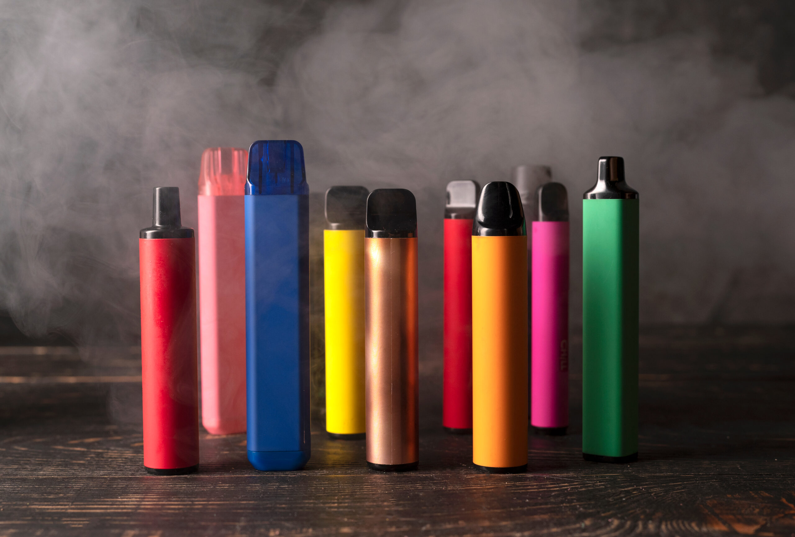 Colorful disposable vape pens with smoke background