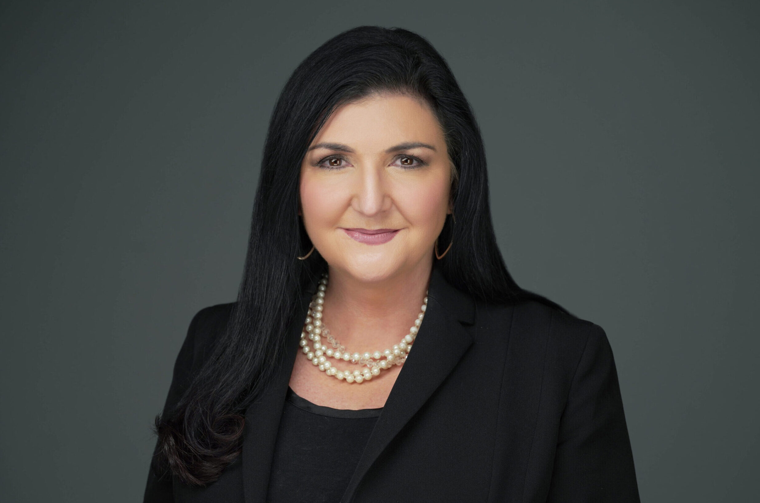 Professional woman in black blazer and pearl necklace