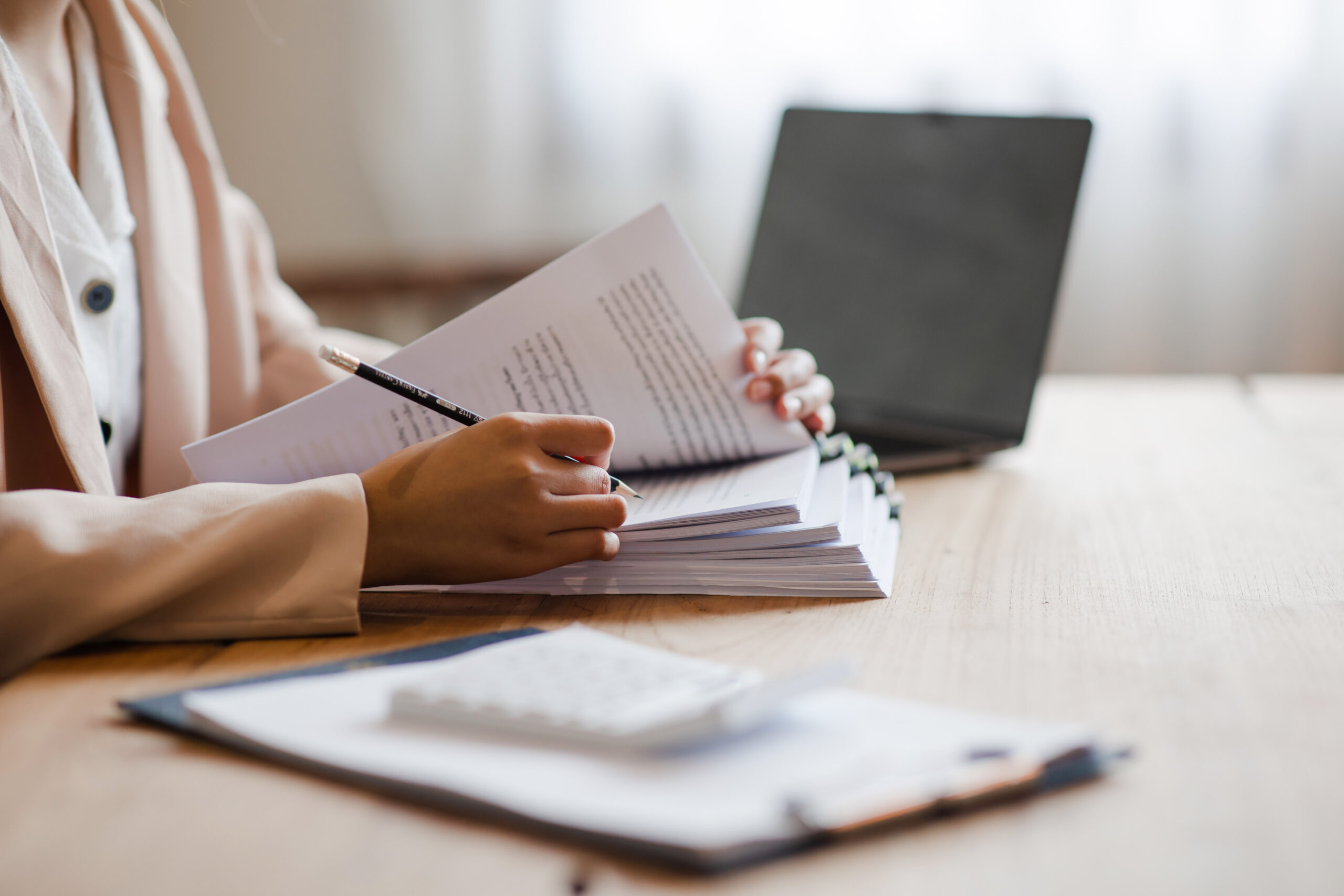 Person reviewing printed documents with pencil at desk