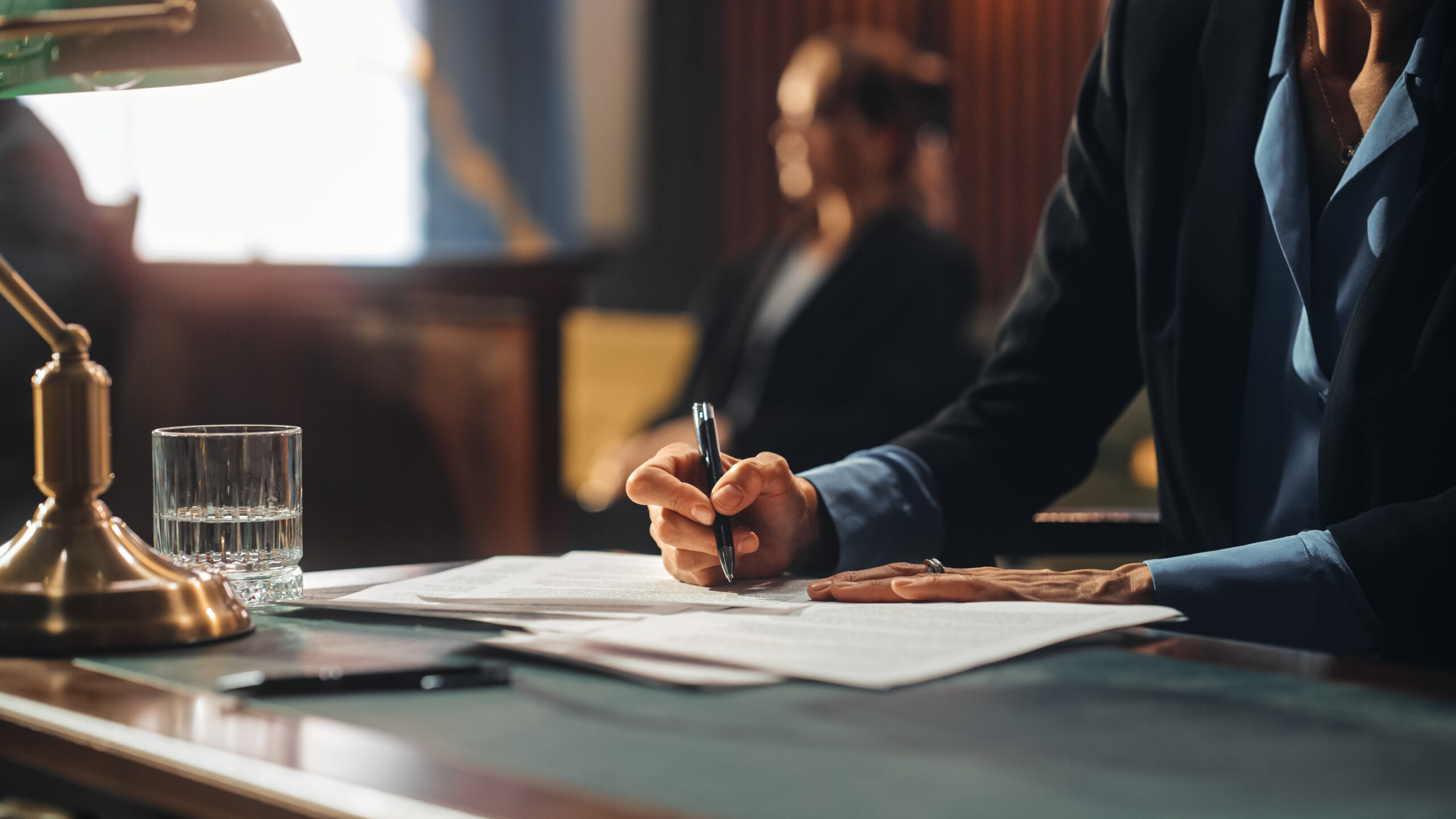 Person signing documents at desk in courtroom