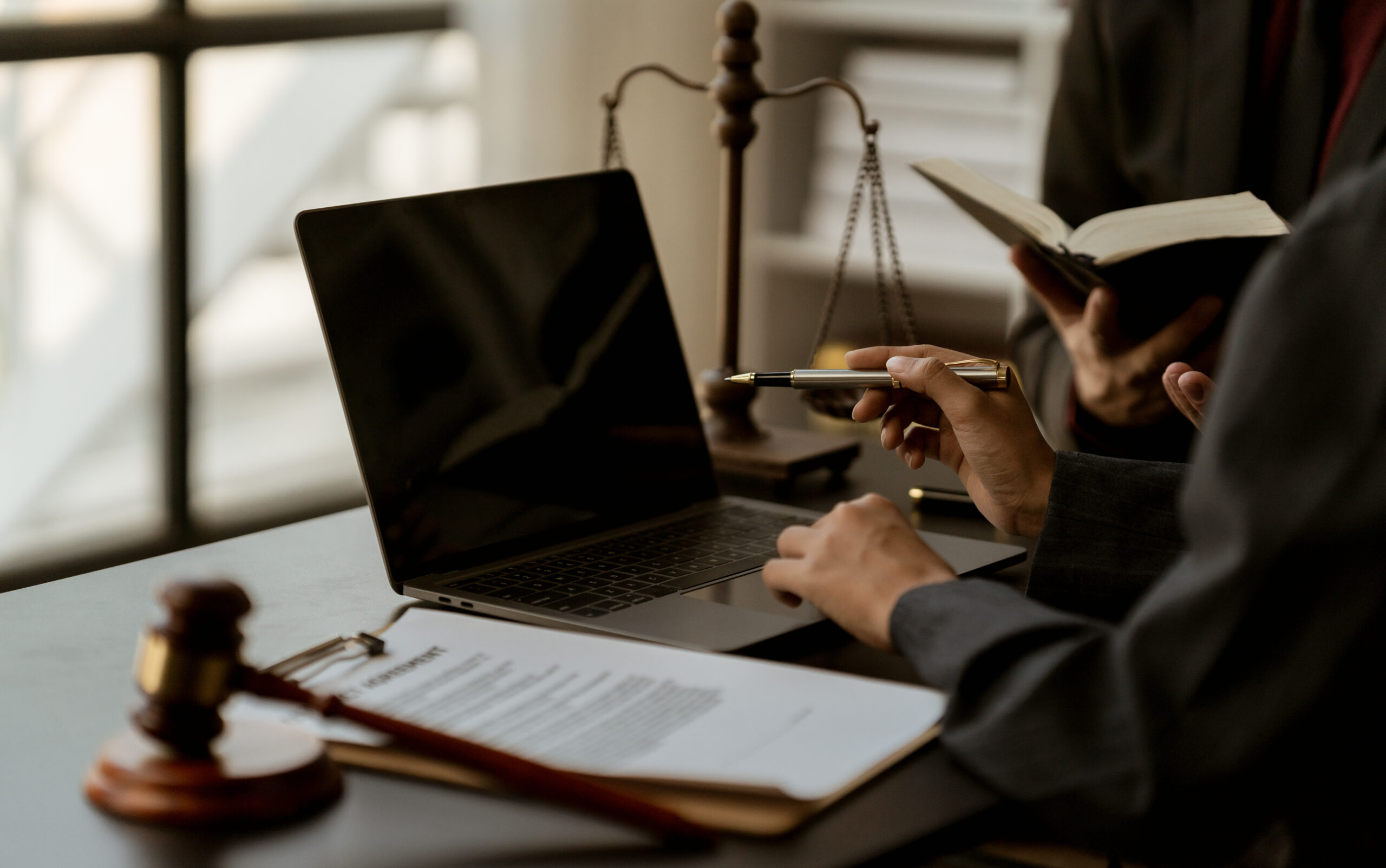 Businessperson holding eyeglasses beside laptop in office