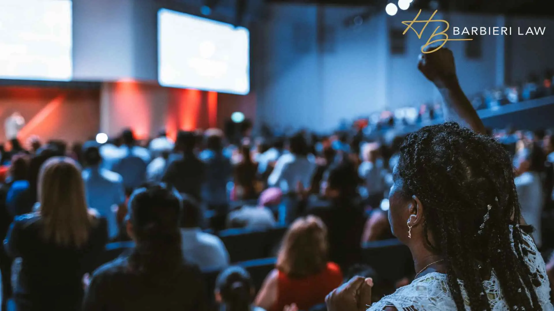 Woman raises fist during crowded indoor conference